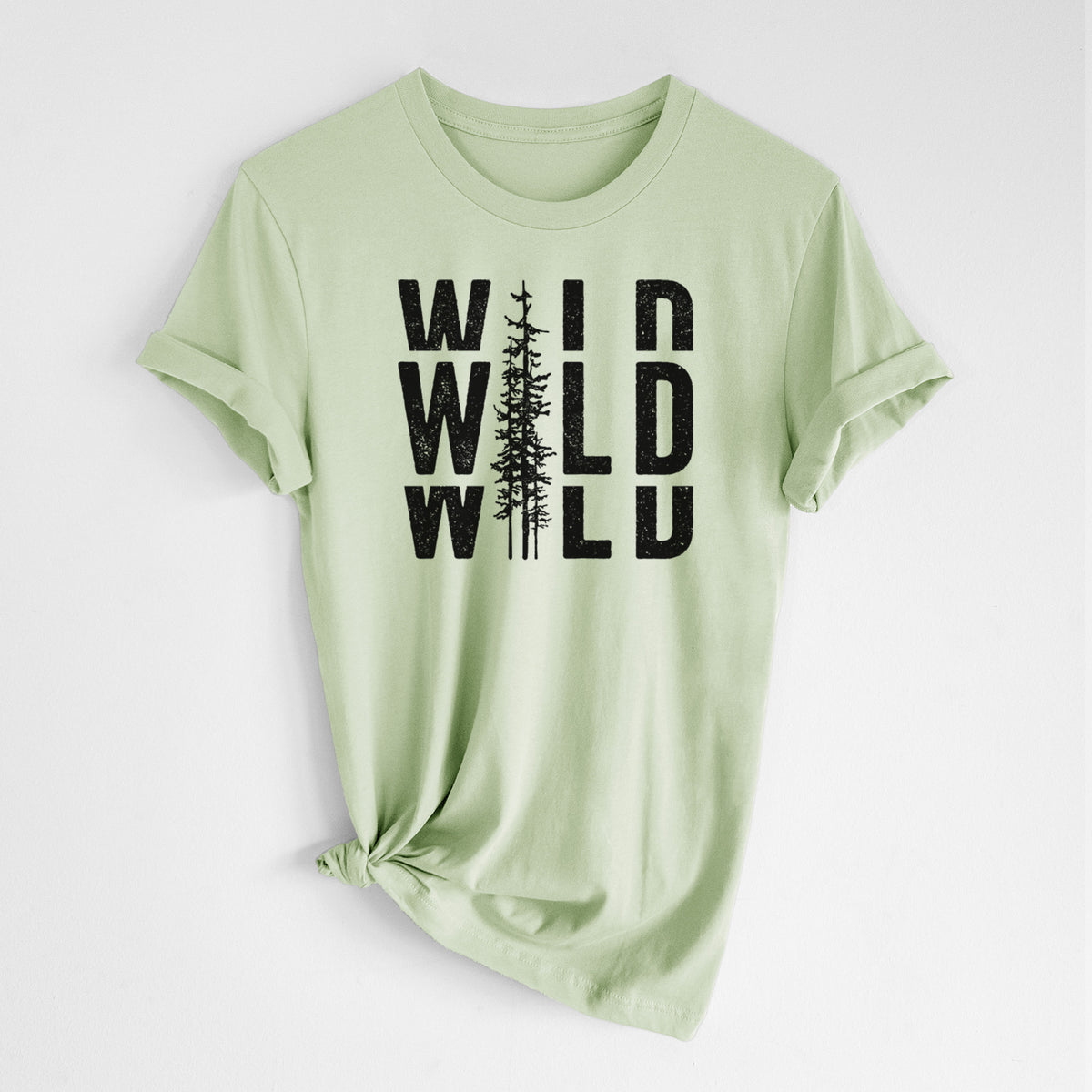 Spring green lightweight cotton t-shirt laid flat with the sleeves rolled, printed with bold black text reading WILD stacked three times, with a tall pine tree forming the letter I.