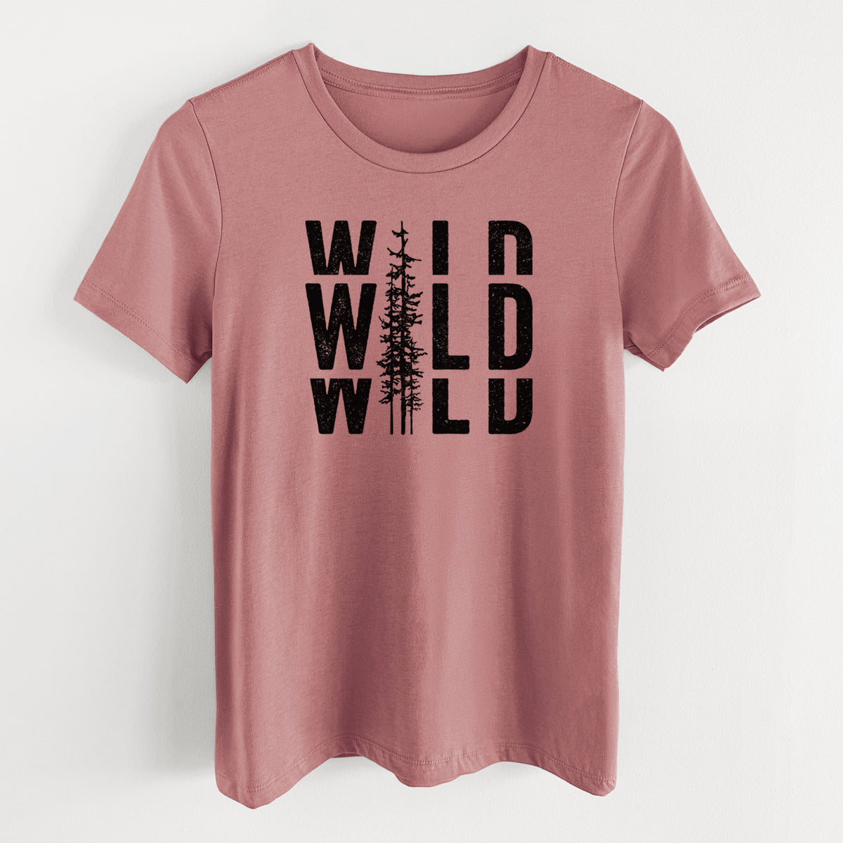 Mauve pink women's relaxed fit cotton t-shirt laid flat, printed with bold black text reading WILD stacked three times, with a tall pine tree forming the letter I.