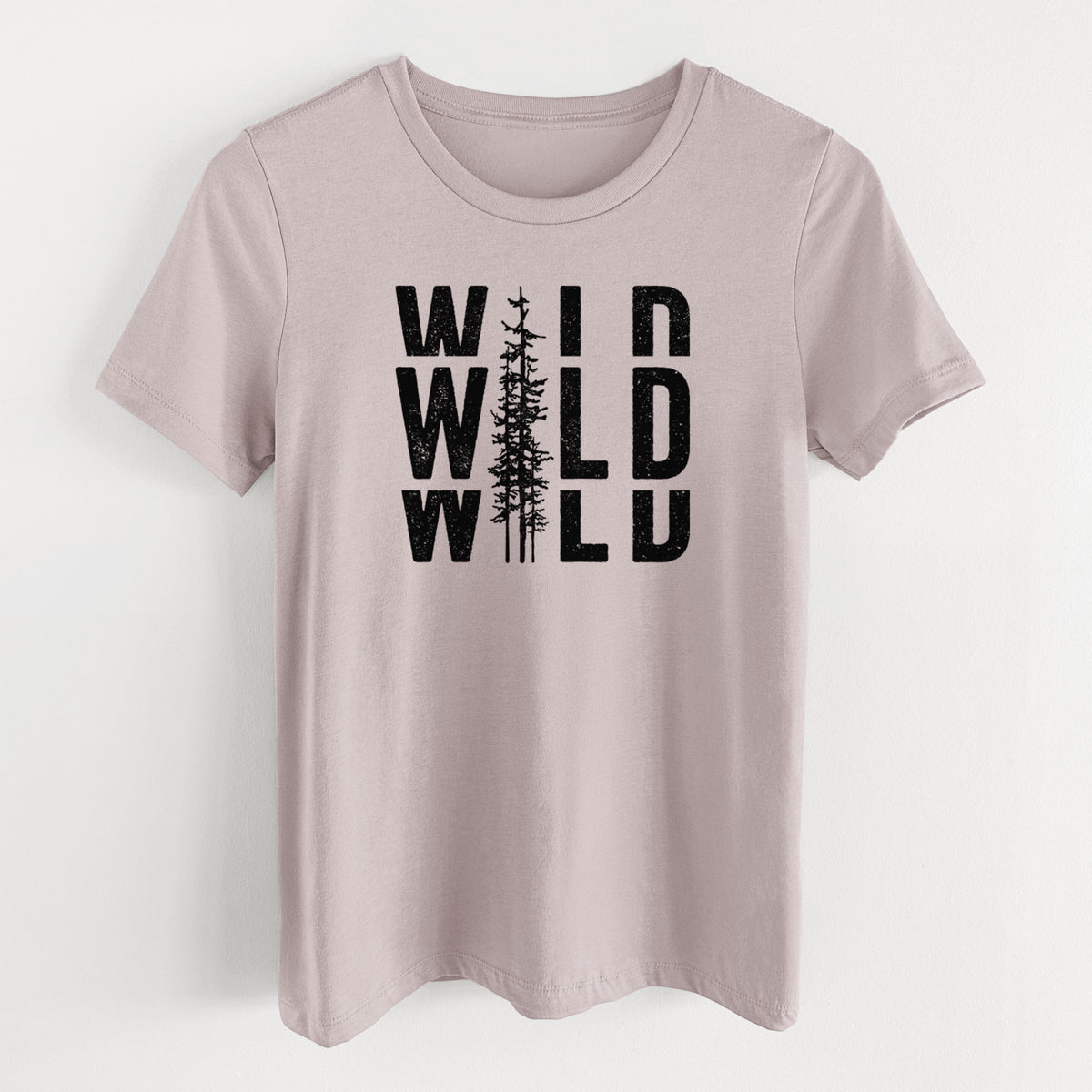 Pink gravel women's relaxed fit cotton t-shirt laid flat, printed with bold black text reading WILD stacked three times, with a tall pine tree forming the letter I.