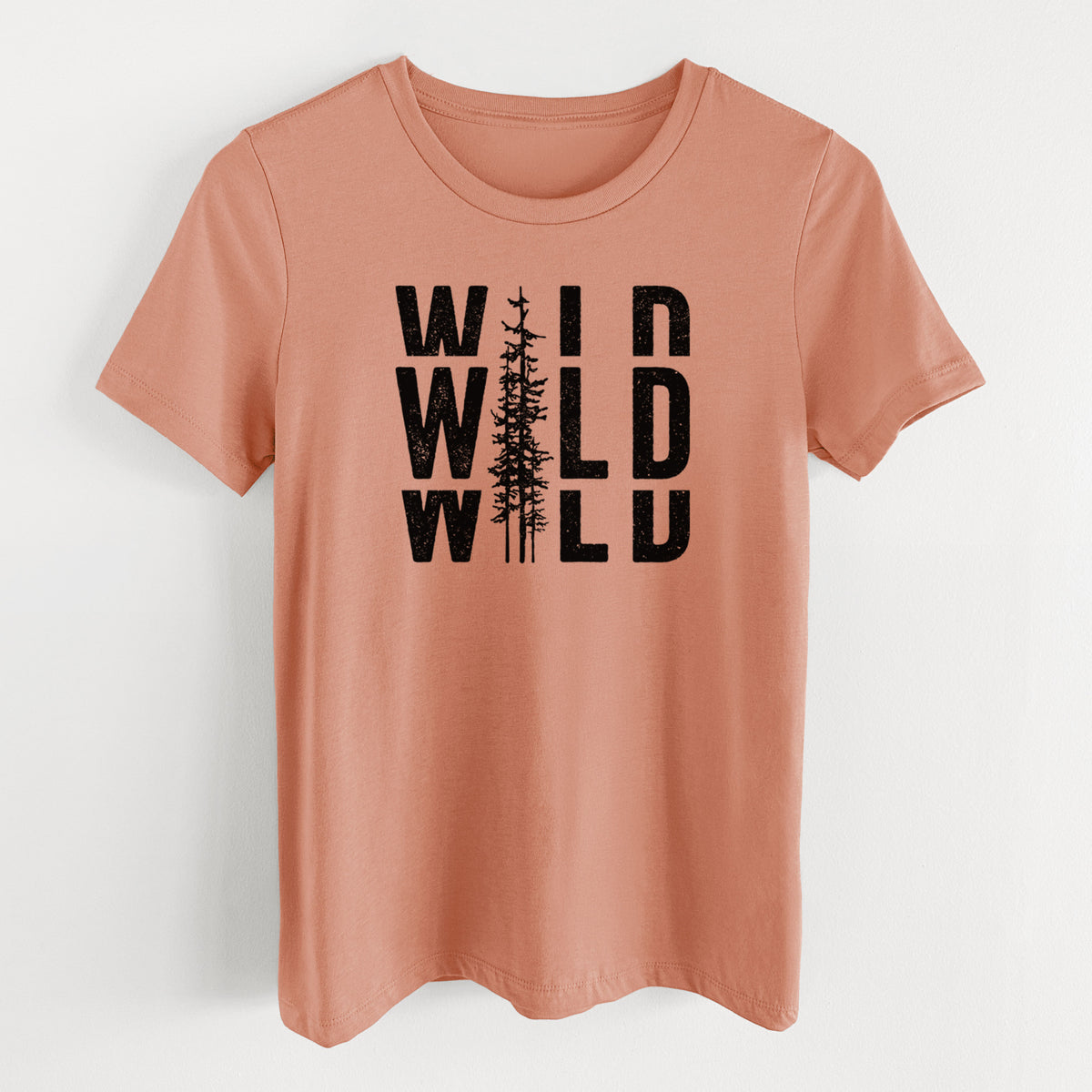 Terracotta orange women's relaxed fit cotton t-shirt laid flat, printed with bold black text reading WILD stacked three times, with a tall pine tree forming the letter I.