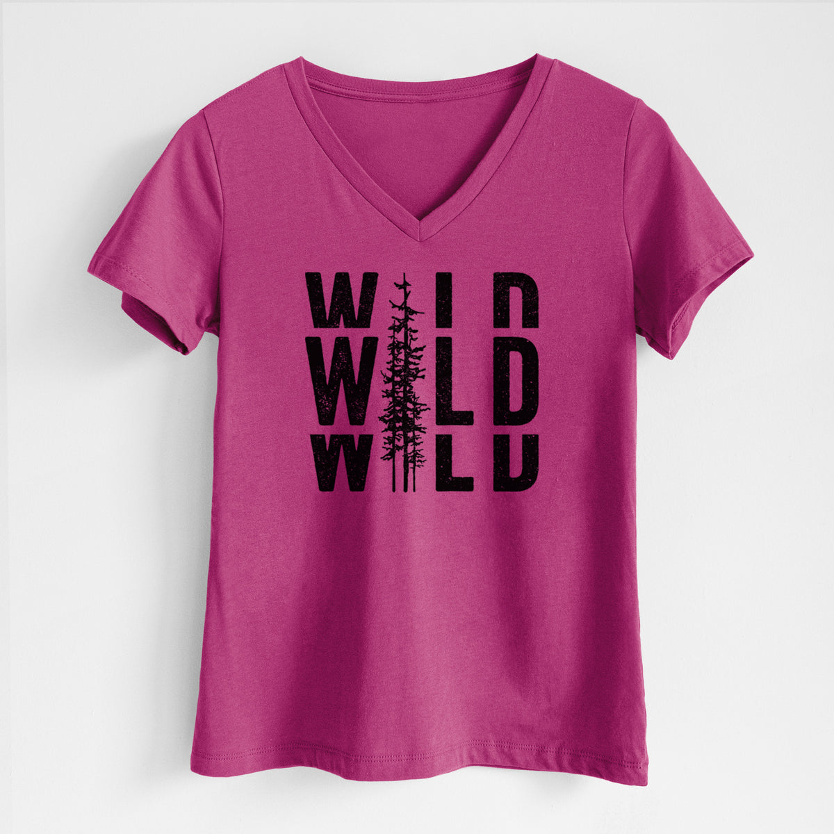 Berry pink women's relaxed fit cotton V-neck t-shirt laid flat, printed with bold black text reading WILD stacked three times, with a tall pine tree forming the letter I.