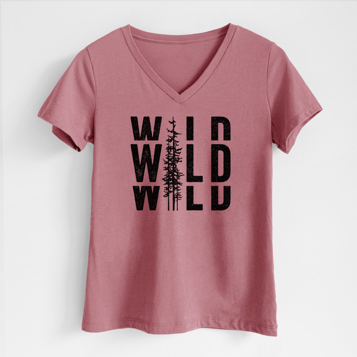 Mauve pink women's relaxed fit cotton V-neck t-shirt laid flat, printed with bold black text reading WILD stacked three times, with a tall pine tree forming the letter I.