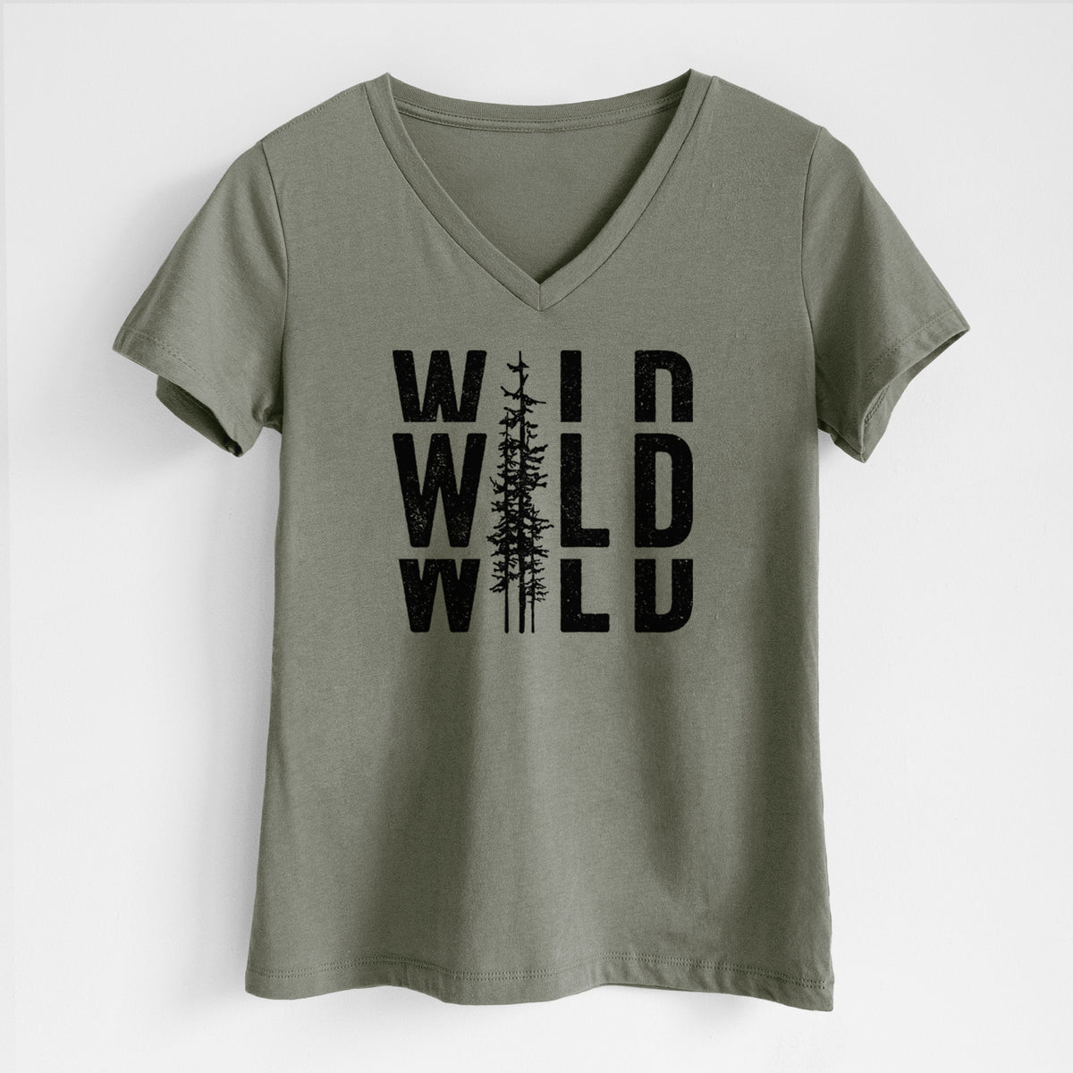 Military green women's relaxed fit cotton V-neck t-shirt laid flat, printed with bold black text reading WILD stacked three times, with a tall pine tree forming the letter I.
