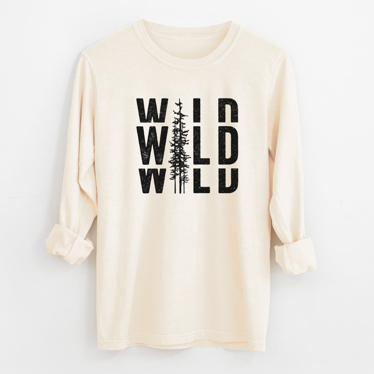Ivory Comfort Colors long sleeve shirt laid flat with the cuffs rolled, printed with bold black text reading WILD stacked three times, with a tall pine tree forming the letter I.