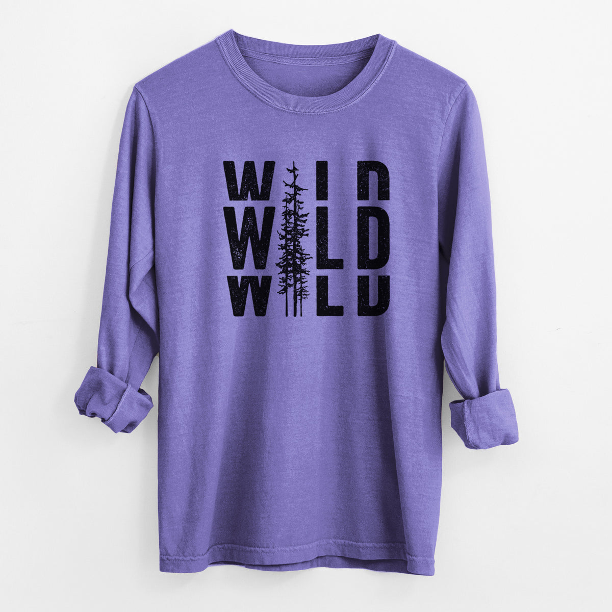 Violet purple Comfort Colors long sleeve shirt laid flat with the cuffs rolled, printed with bold black text reading WILD stacked three times, with a tall pine tree forming the letter I.