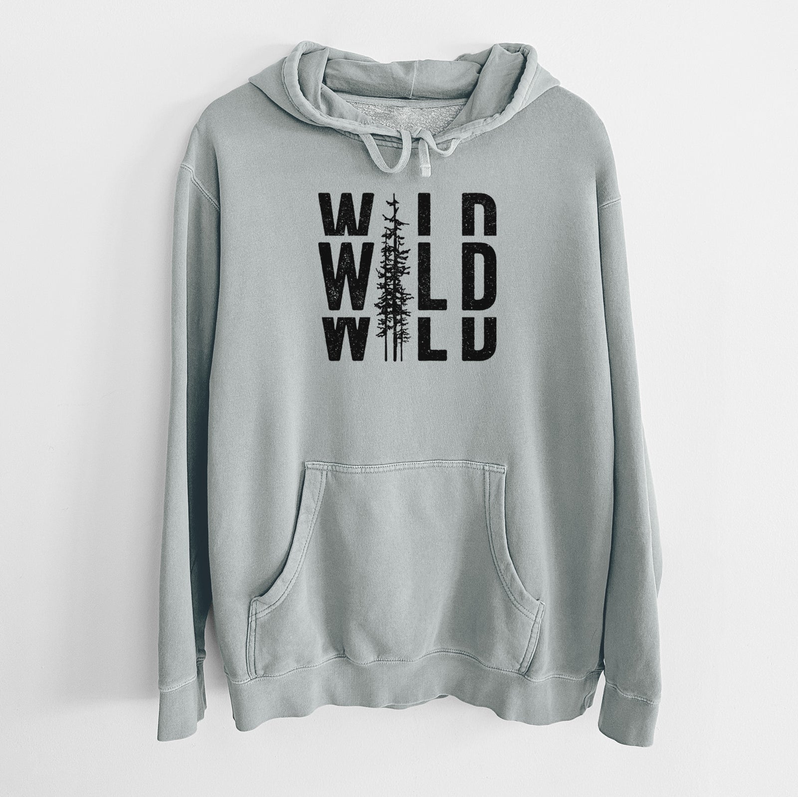 Sage green pigment dyed hoodie laid flat, printed with bold black text reading WILD stacked three times, with a tall pine tree forming the letter I.