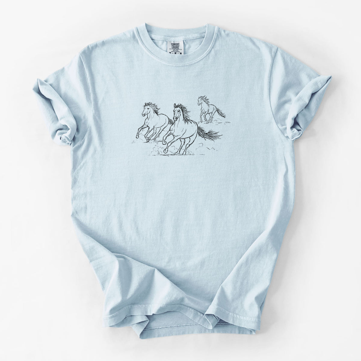 Chambray blue Comfort Colors t-shirt laid flat, printed with a black ink illustration of three wild horses galloping.