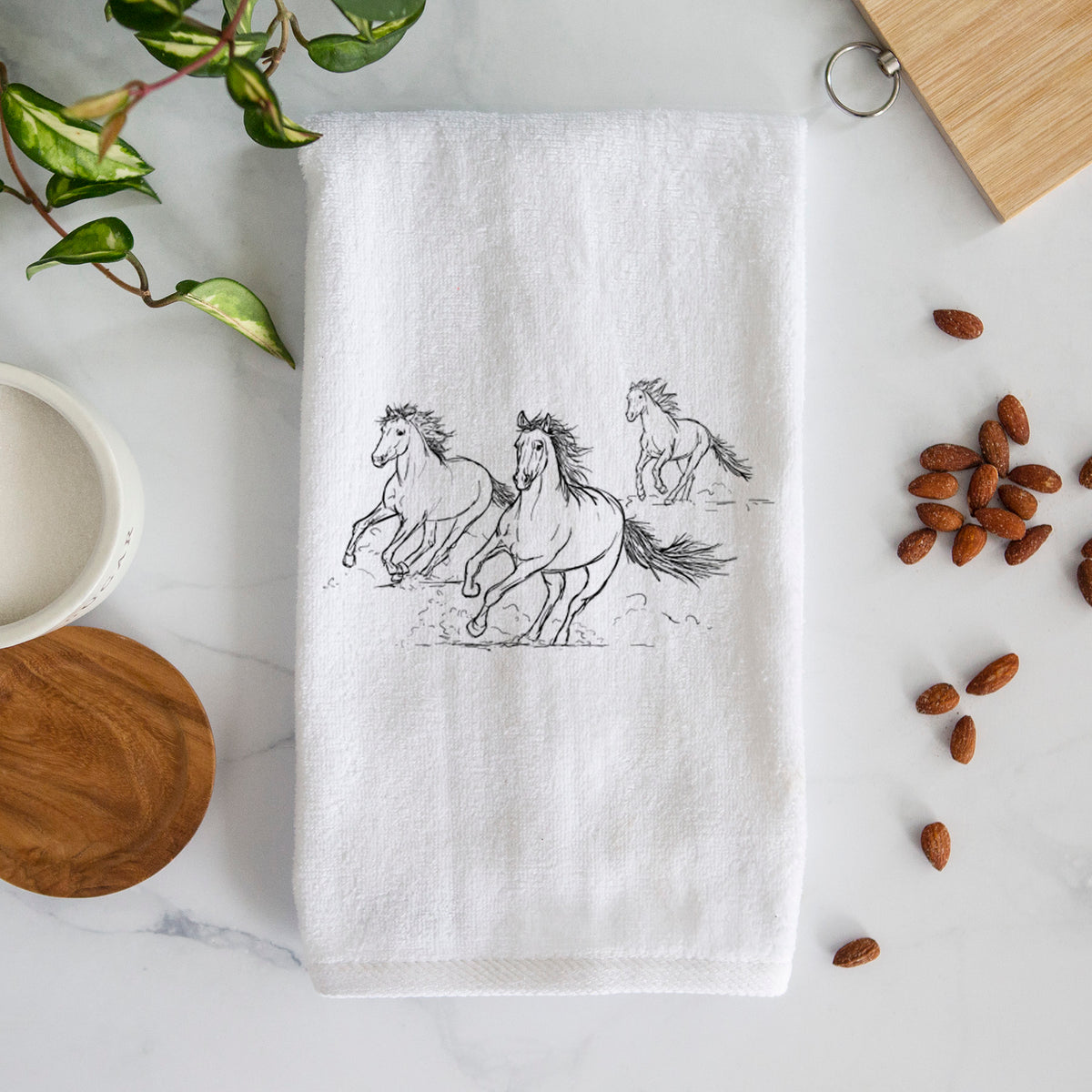 White hand towel printed with a black ink illustration of three wild horses galloping.