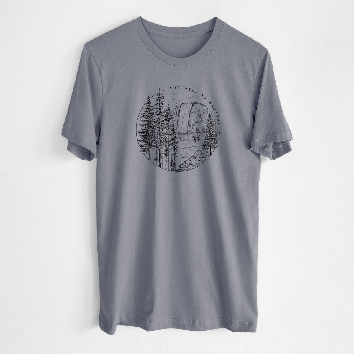 Storm grey lightweight cotton t-shirt laid flat, printed with a round black ink scene of a waterfall, pine trees and a river, with the words The Wild Is Waiting.