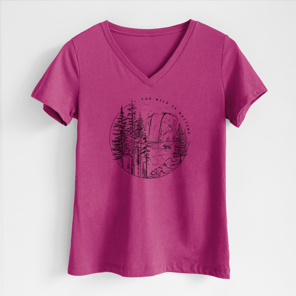 Berry pink women's relaxed fit cotton V-neck t-shirt laid flat, printed with a round black ink scene of a waterfall, pine trees and a river, with the words The Wild Is Waiting.