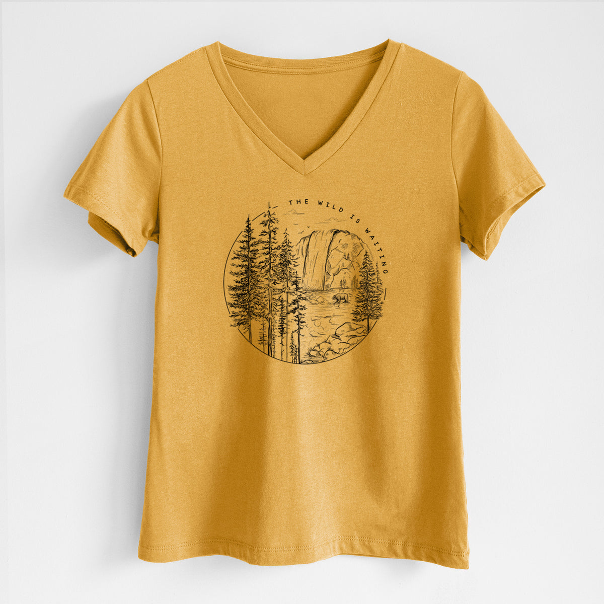 Honeycomb yellow women's relaxed fit cotton V-neck t-shirt laid flat, printed with a round black ink scene of a waterfall, pine trees and a river, with the words The Wild Is Waiting.