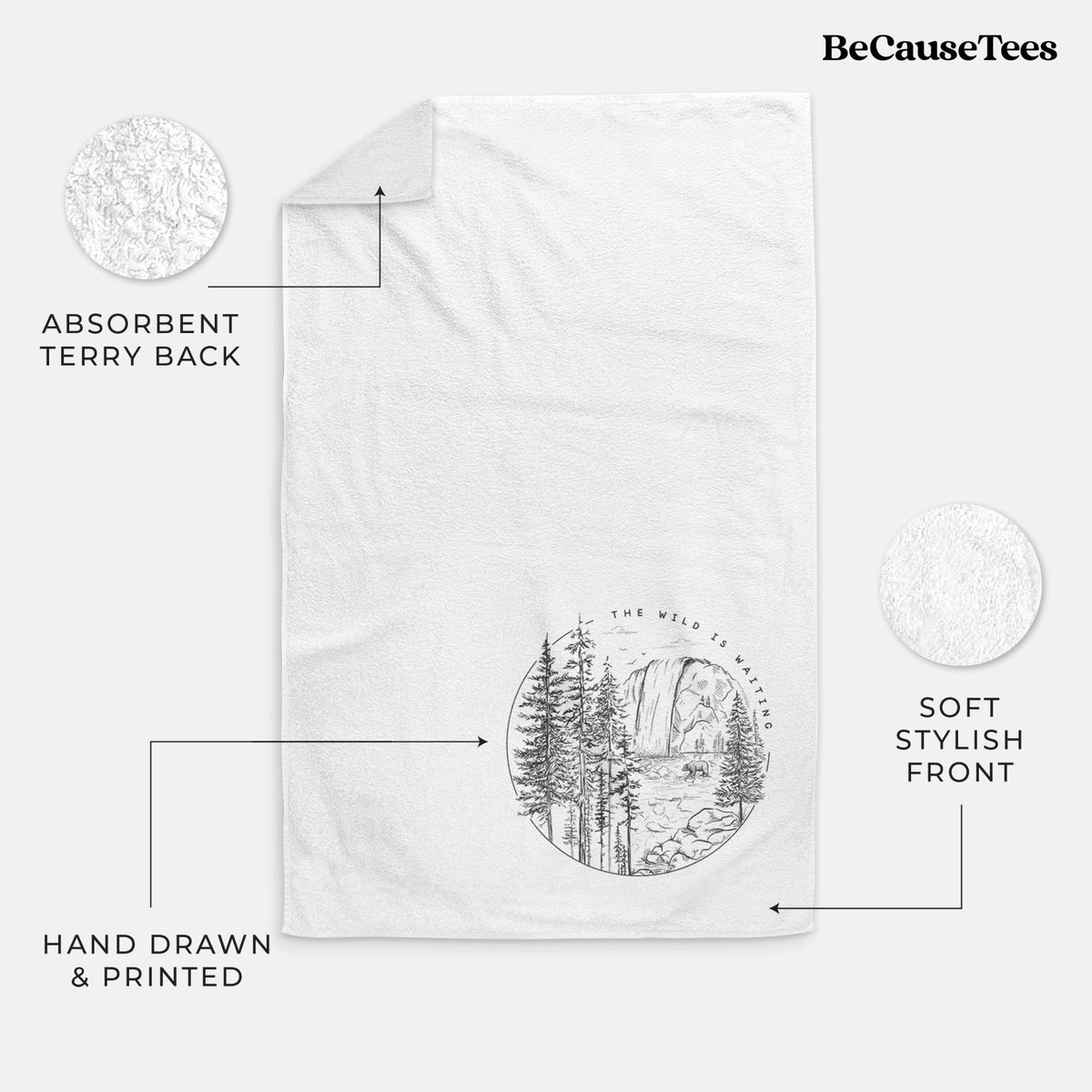 White hand towel printed with a round black ink scene of a waterfall, pine trees and a river, with the words The Wild Is Waiting.