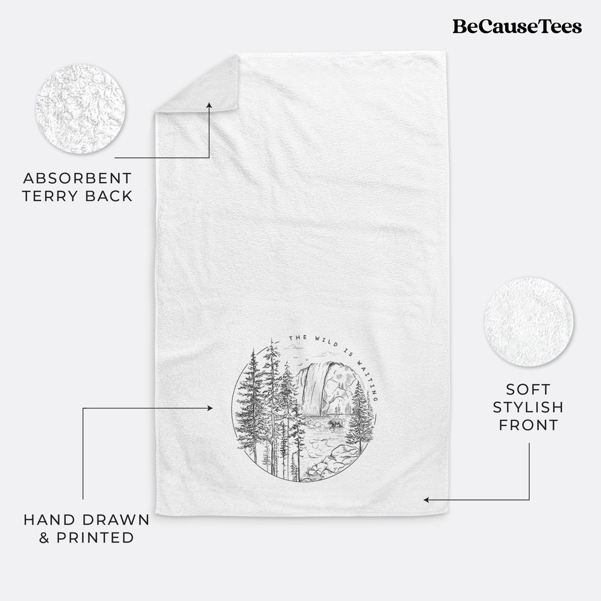 White hand towel printed with a round black ink scene of a waterfall, pine trees and a river, with the words The Wild Is Waiting.