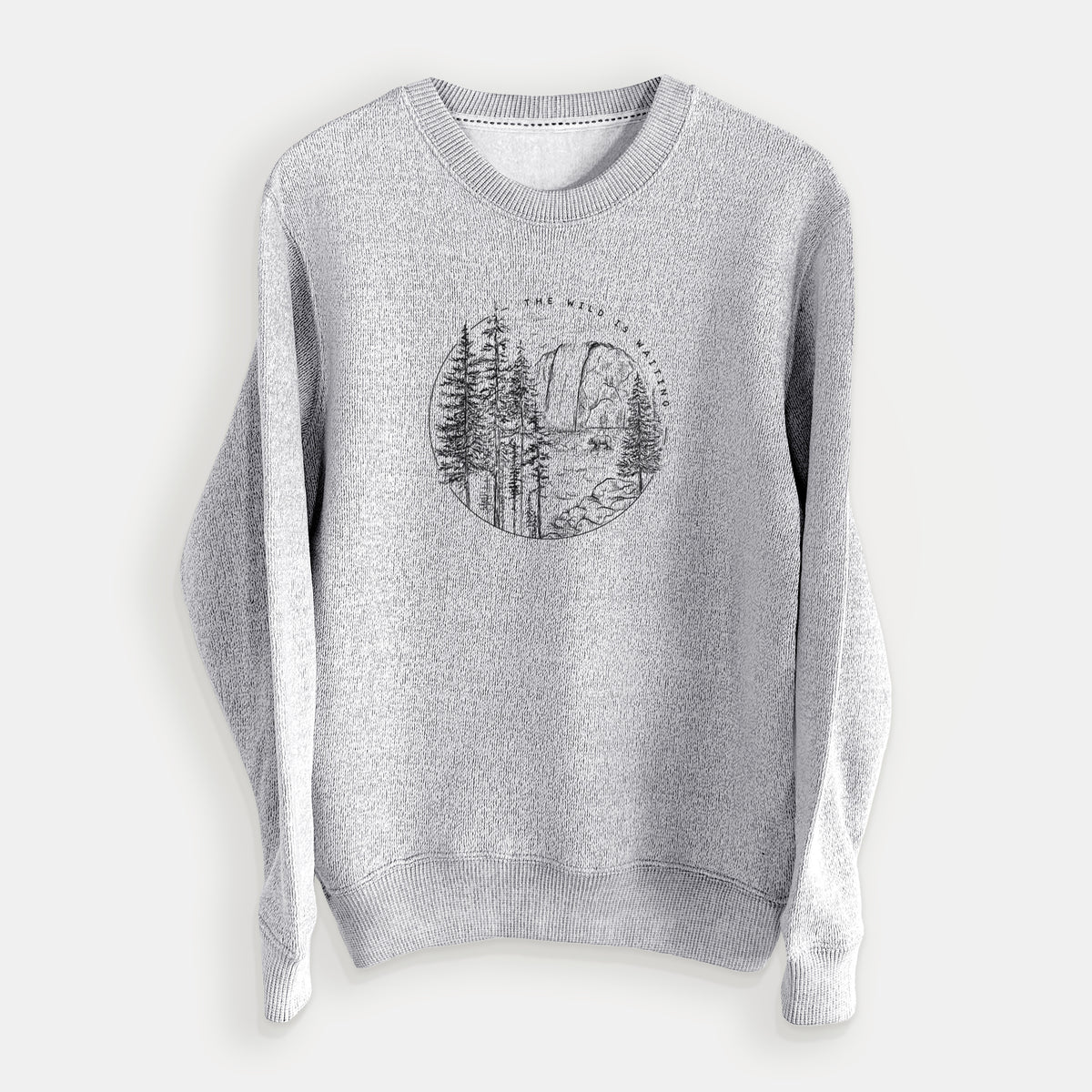 Salt and pepper knit sweatshirt laid flat, printed with a round black ink scene of a waterfall, pine trees and a river, with the words The Wild Is Waiting.