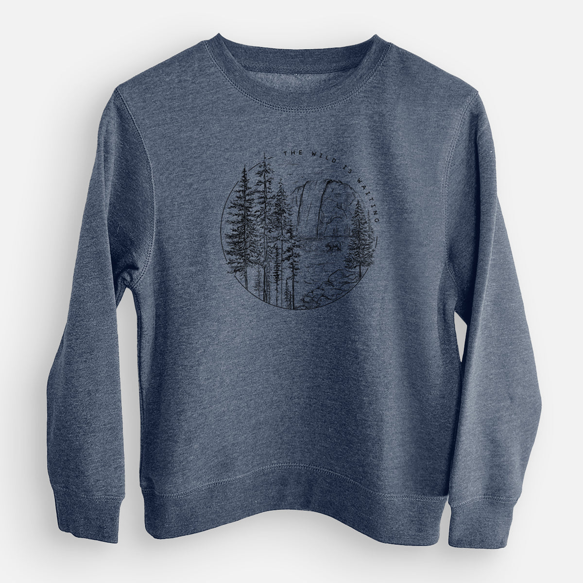 Storm blue youth crewneck sweatshirt laid flat, printed with a round black ink scene of a waterfall, pine trees and a river, with the words The Wild Is Waiting.