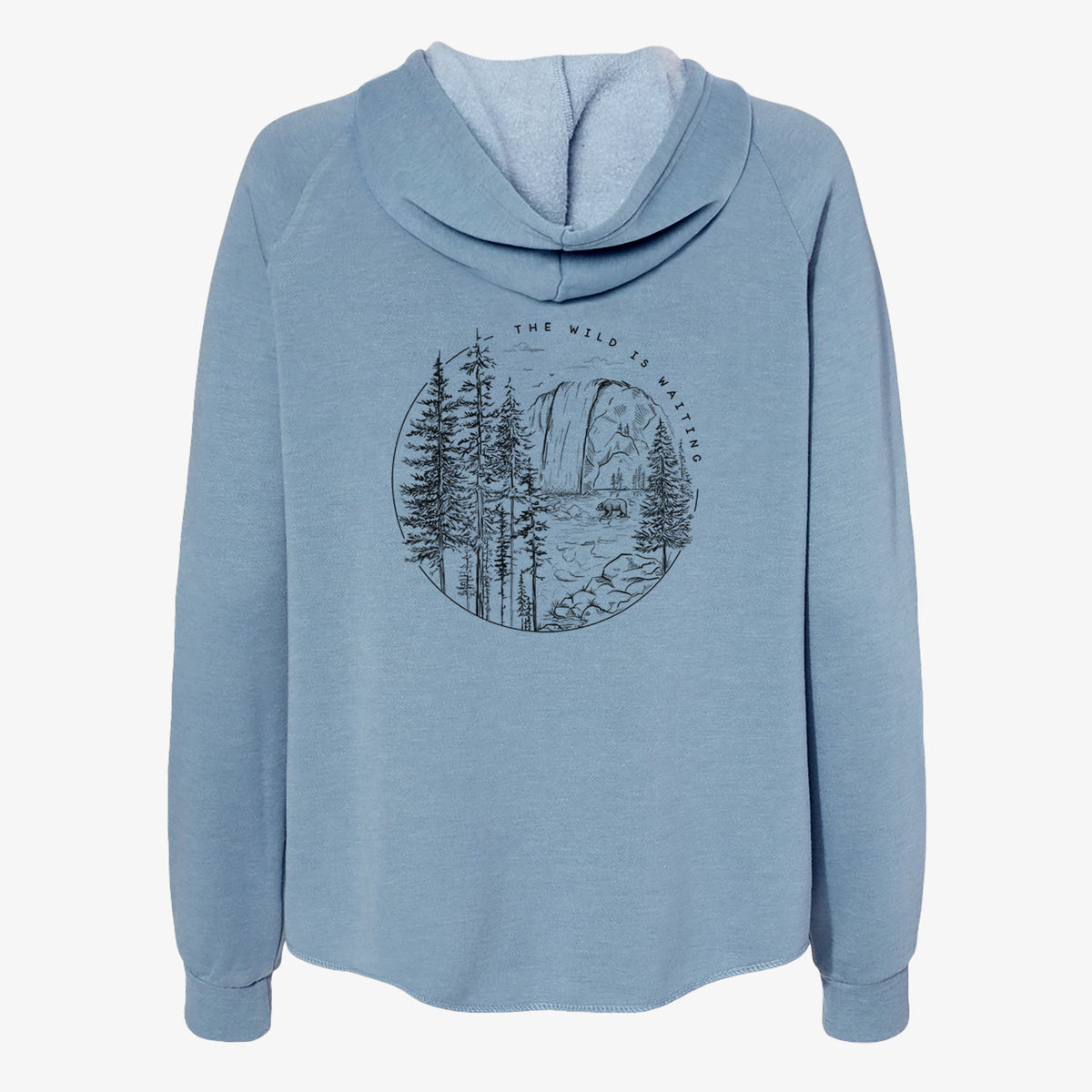 Misty blue women's Cali Wave zip-up sweatshirt laid flat, printed with a round black ink scene of a waterfall, pine trees and a river, with the words The Wild Is Waiting.