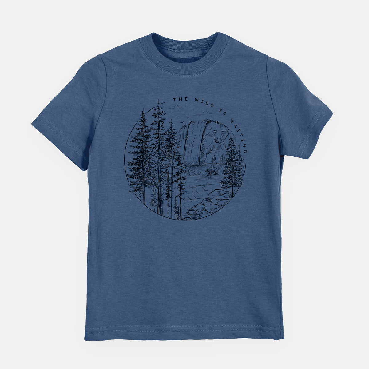Indigo blue youth t-shirt laid flat, printed with a round black ink scene of a waterfall, pine trees and a river, with the words The Wild Is Waiting.