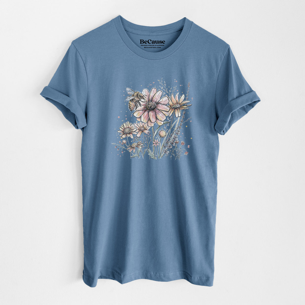 Steel blue lightweight cotton t-shirt laid flat, printed with a soft full-color illustration of a bee flying over pink and purple wildflowers.