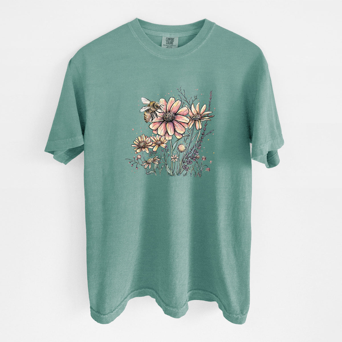 Reef green Comfort Colors t-shirt laid flat, printed with a soft full-color illustration of a bee flying over pink and purple wildflowers.