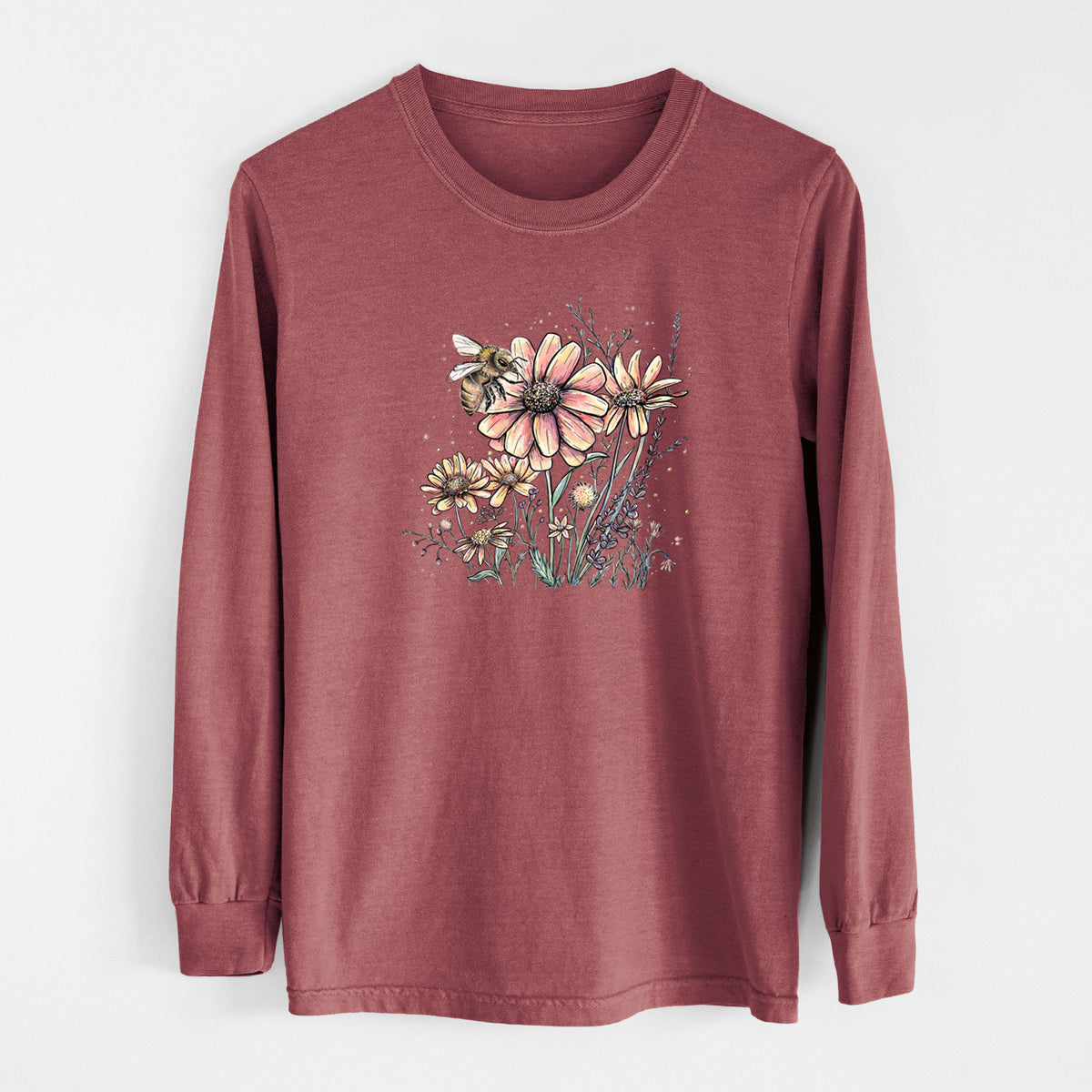 Brick red Comfort Colors long sleeve shirt laid flat, printed with a soft full-color illustration of a bee flying over pink and purple wildflowers.