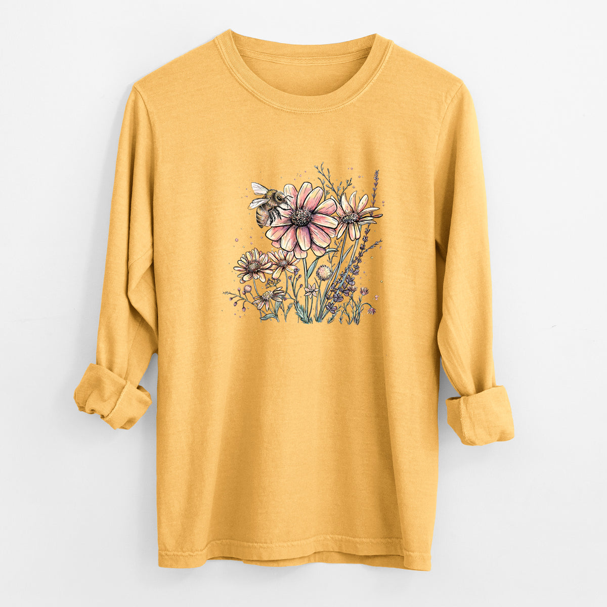 Golden wheat yellow Comfort Colors long sleeve shirt laid flat with the cuffs rolled, printed with a soft full-color illustration of a bee flying over pink and purple wildflowers.