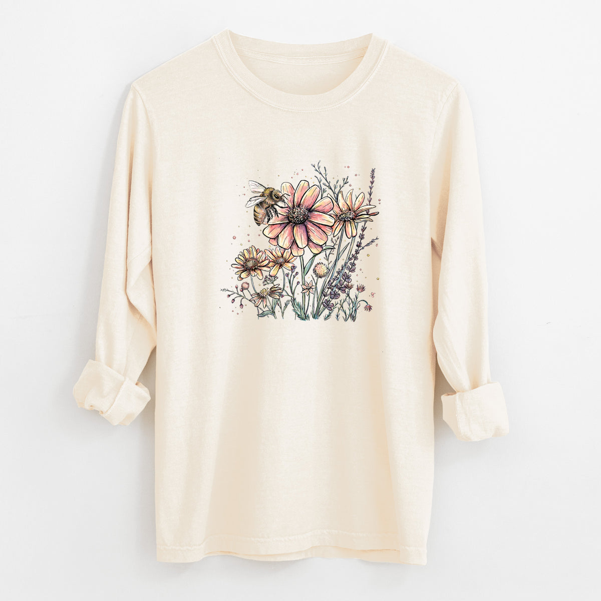 Ivory Comfort Colors long sleeve shirt laid flat with the cuffs rolled, printed with a soft full-color illustration of a bee flying over pink and purple wildflowers.