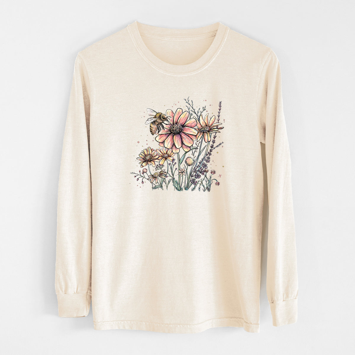 Ivory Comfort Colors long sleeve shirt laid flat, printed with a soft full-color illustration of a bee flying over pink and purple wildflowers.