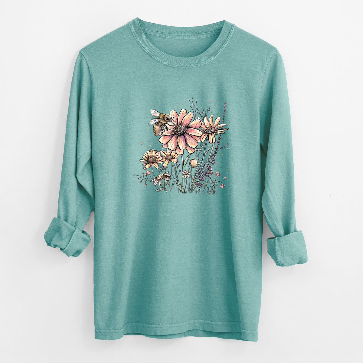 Reef green Comfort Colors long sleeve shirt laid flat with the cuffs rolled, printed with a soft full-color illustration of a bee flying over pink and purple wildflowers.