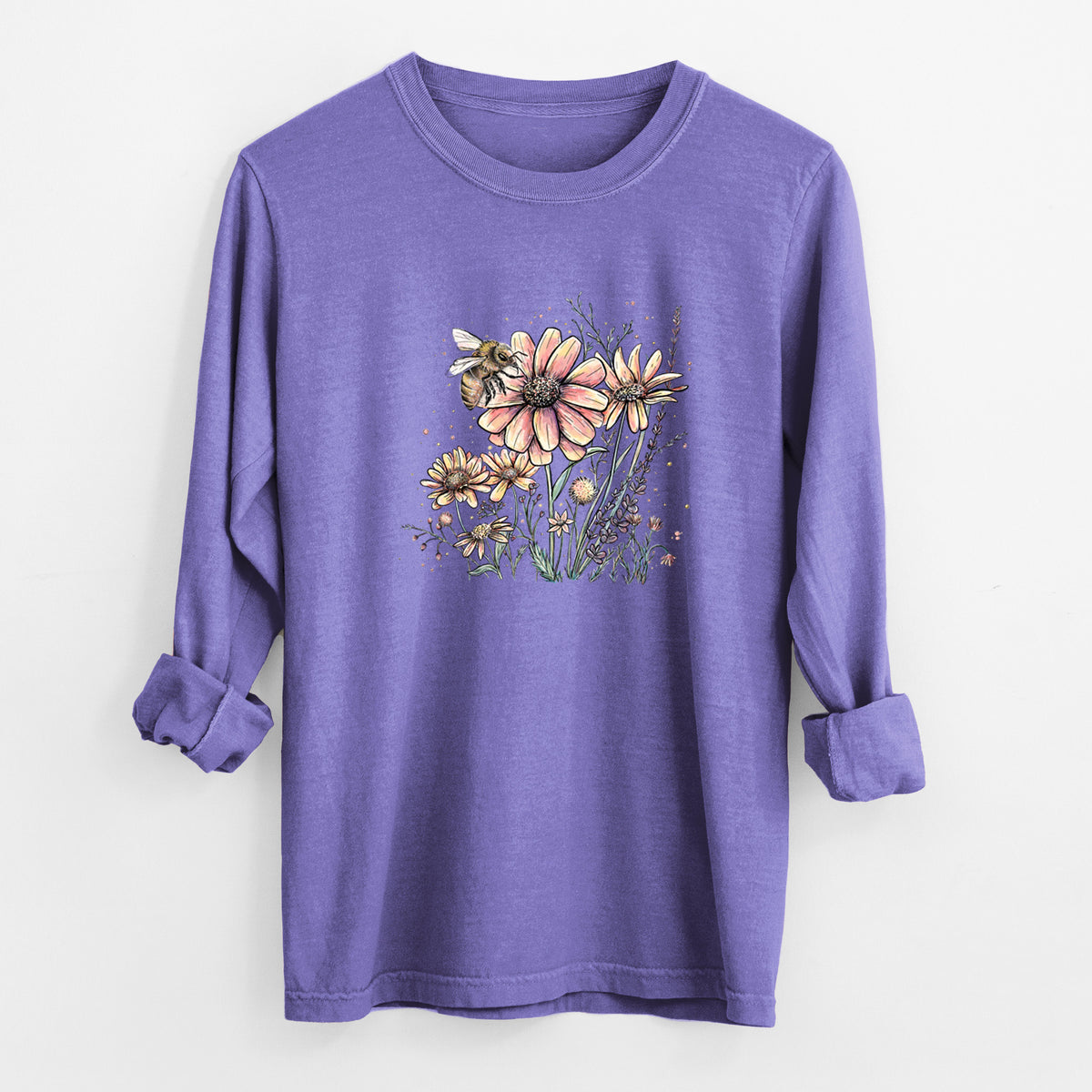 Violet purple Comfort Colors long sleeve shirt laid flat with the cuffs rolled, printed with a soft full-color illustration of a bee flying over pink and purple wildflowers.