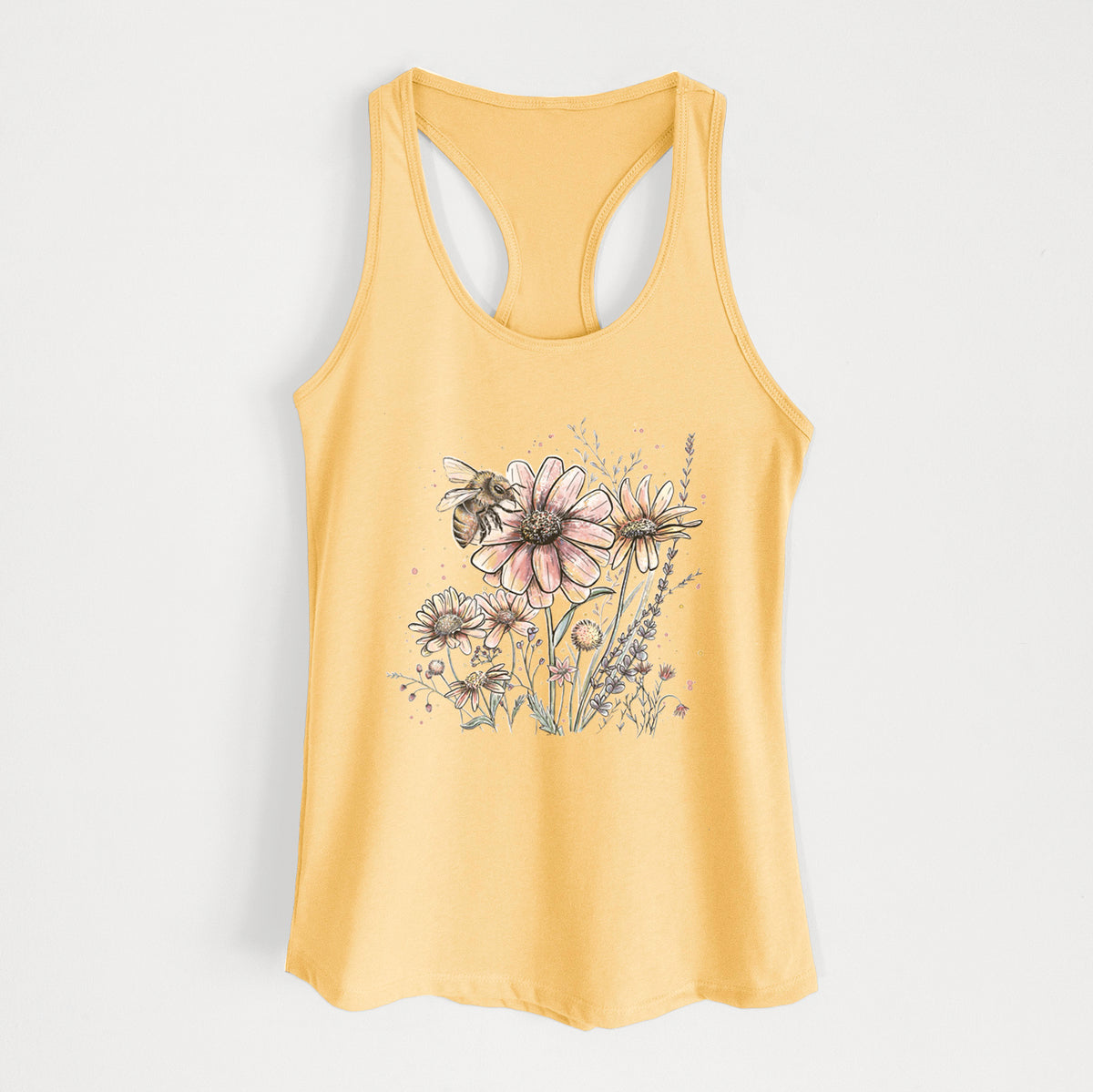 Banana cream women's racerback tank top laid flat, printed with a soft full-color illustration of a bee flying over pink and purple wildflowers.