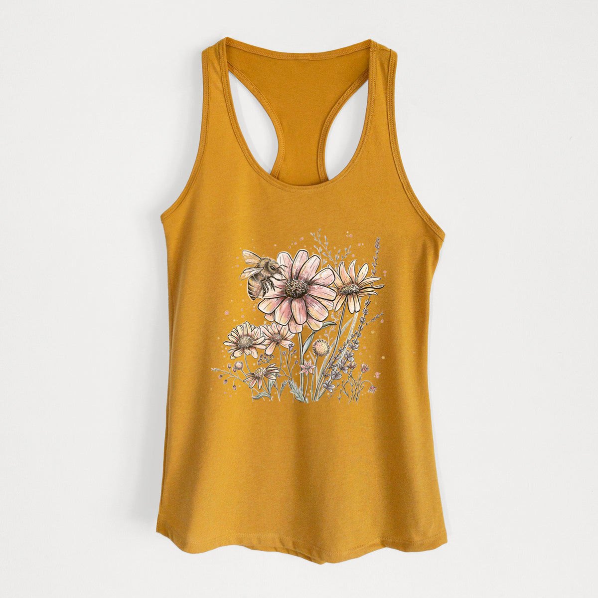 Gold women's racerback tank top laid flat, printed with a soft full-color illustration of a bee flying over pink and purple wildflowers.