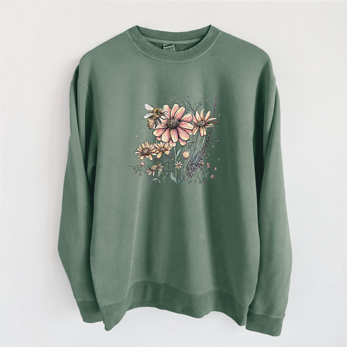 Alpine green pigment dyed crewneck sweatshirt laid flat, printed with a soft full-color illustration of a bee flying over pink and purple wildflowers.