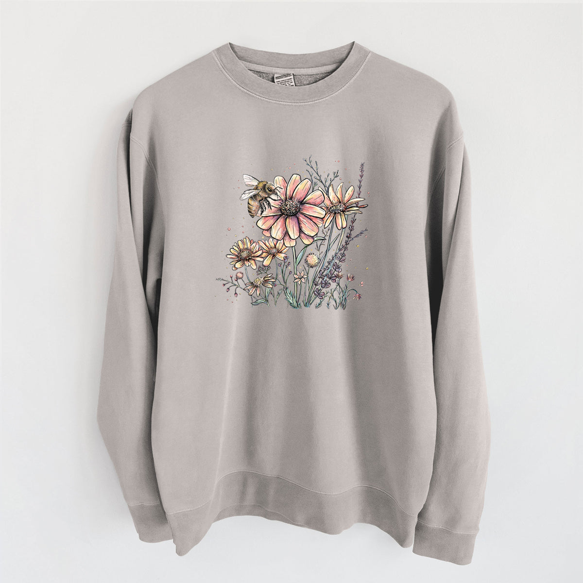 Cement grey pigment dyed crewneck sweatshirt laid flat, printed with a soft full-color illustration of a bee flying over pink and purple wildflowers.