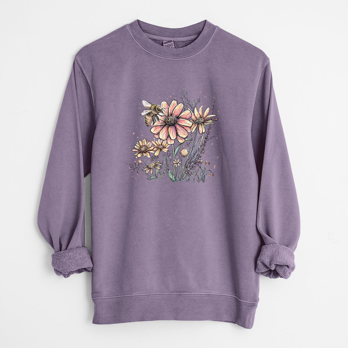 Plum purple pigment dyed crewneck sweatshirt laid flat with the sleeves rolled, printed with a soft full-color illustration of a bee flying over pink and purple wildflowers.