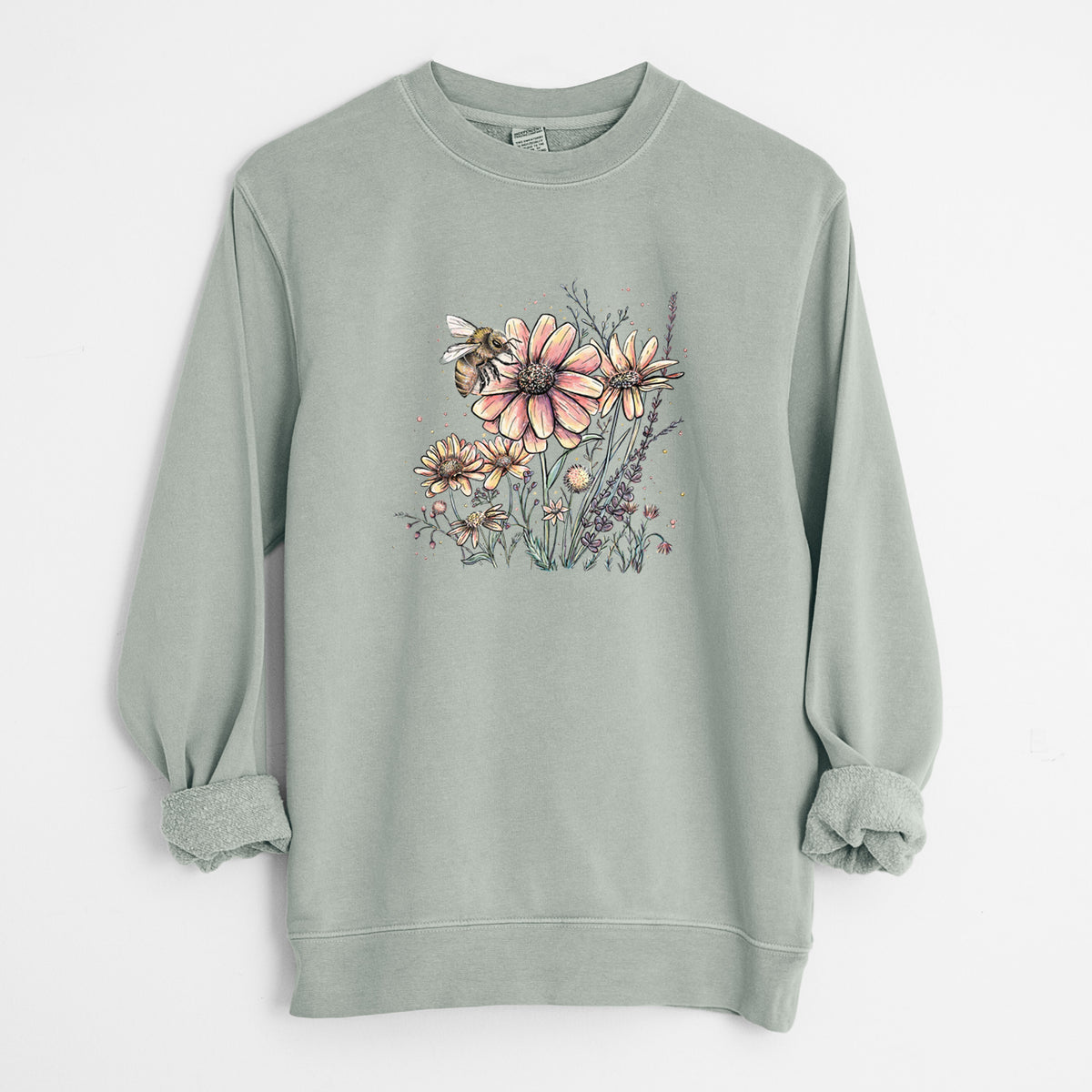 Sage green pigment dyed crewneck sweatshirt laid flat with the sleeves rolled, printed with a soft full-color illustration of a bee flying over pink and purple wildflowers.