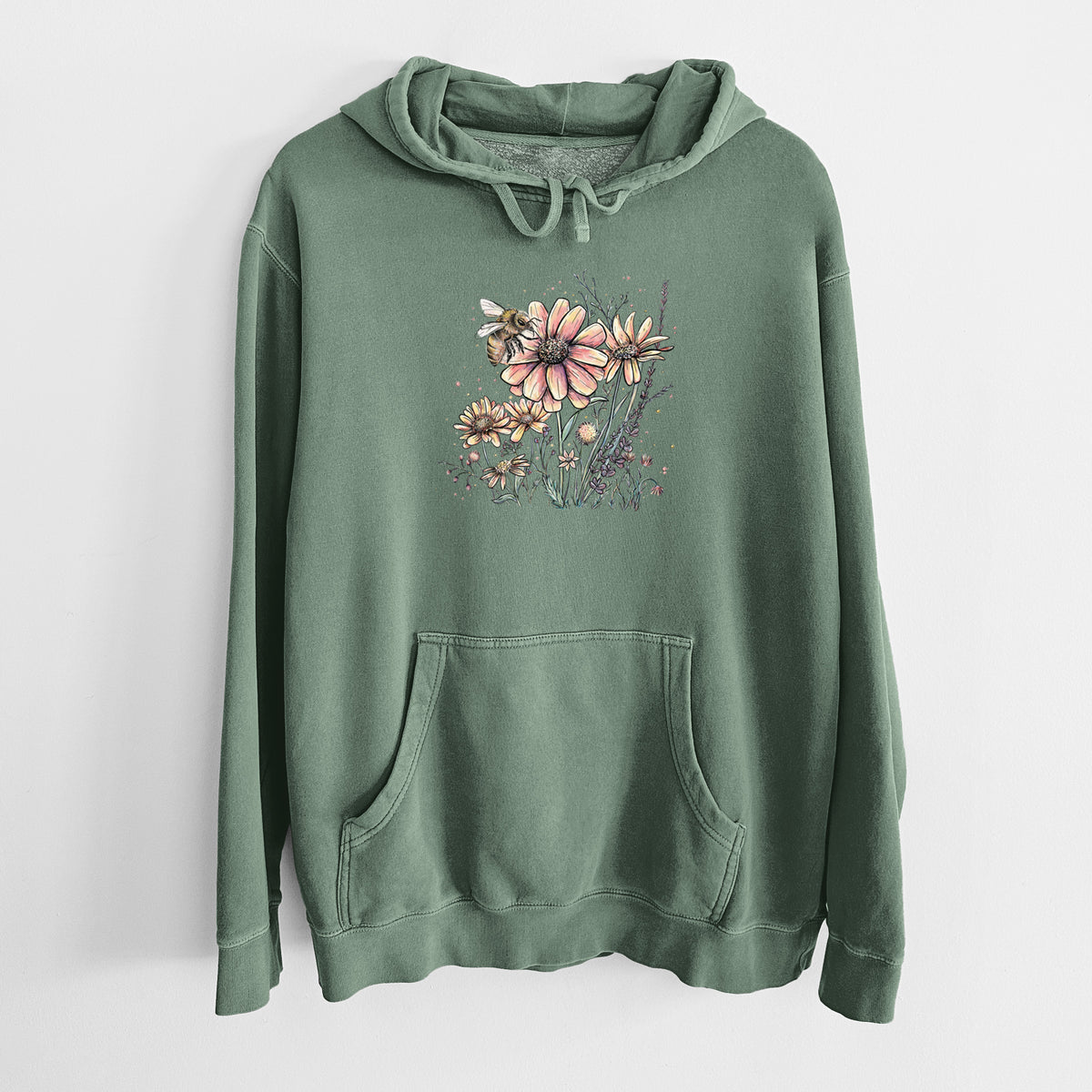 Alpine green pigment dyed hoodie laid flat, printed with a soft full-color illustration of a bee flying over pink and purple wildflowers.