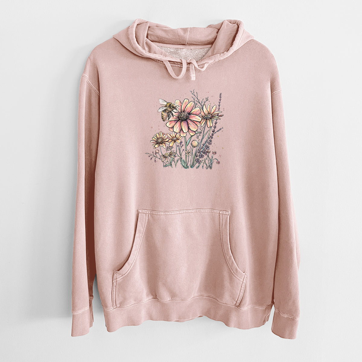 Dusty pink pigment dyed hoodie laid flat, printed with a soft full-color illustration of a bee flying over pink and purple wildflowers.