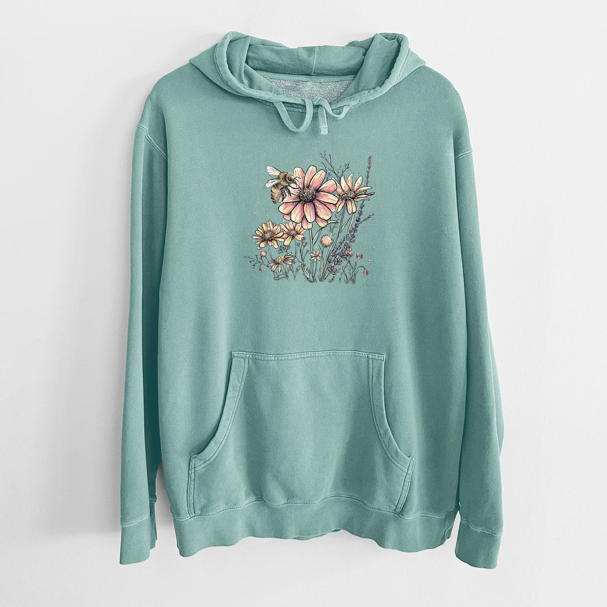 Mint green pigment dyed hoodie laid flat, printed with a soft full-color illustration of a bee flying over pink and purple wildflowers.