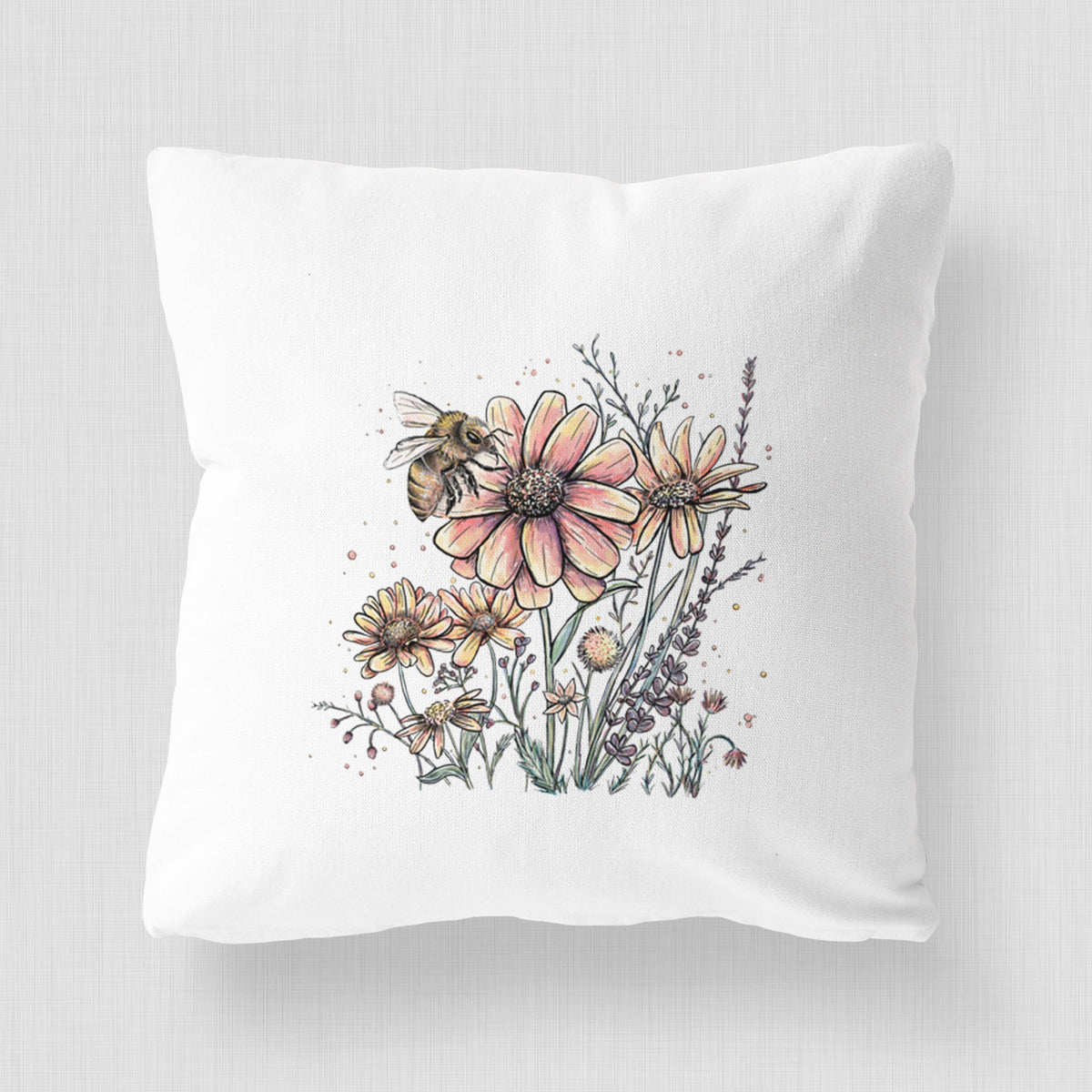 White pillow cover printed with a soft full-color illustration of a bee flying over pink and purple wildflowers.