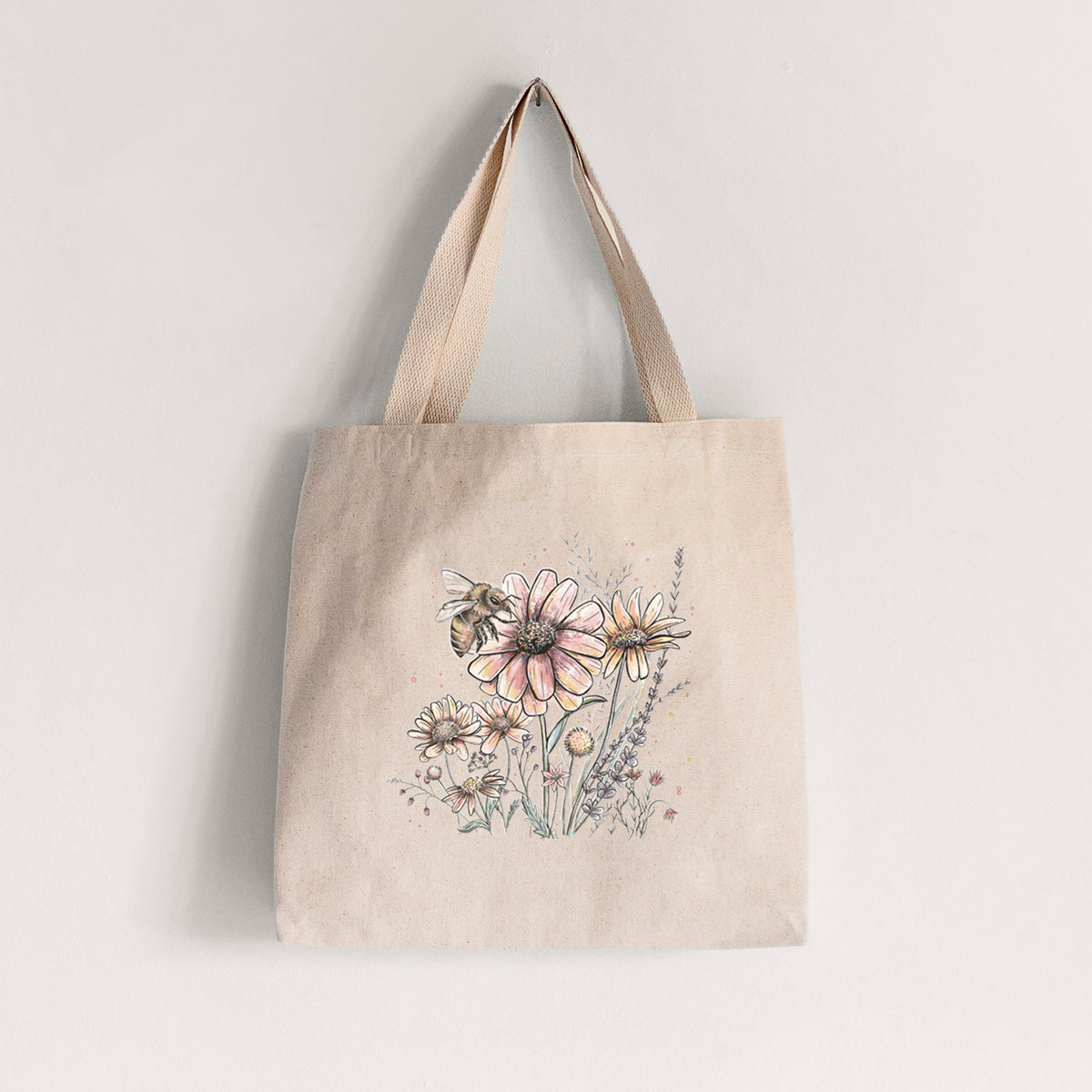 Natural canvas tote bag printed with a soft full-color illustration of a bee flying over pink and purple wildflowers.