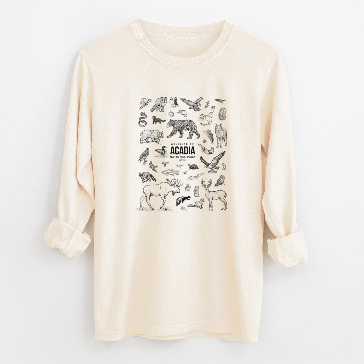 Ivory Comfort Colors long sleeve shirt laid flat with the cuffs rolled, printed with a collection of black ink wildlife illustrations surrounding the words Acadia National Park.