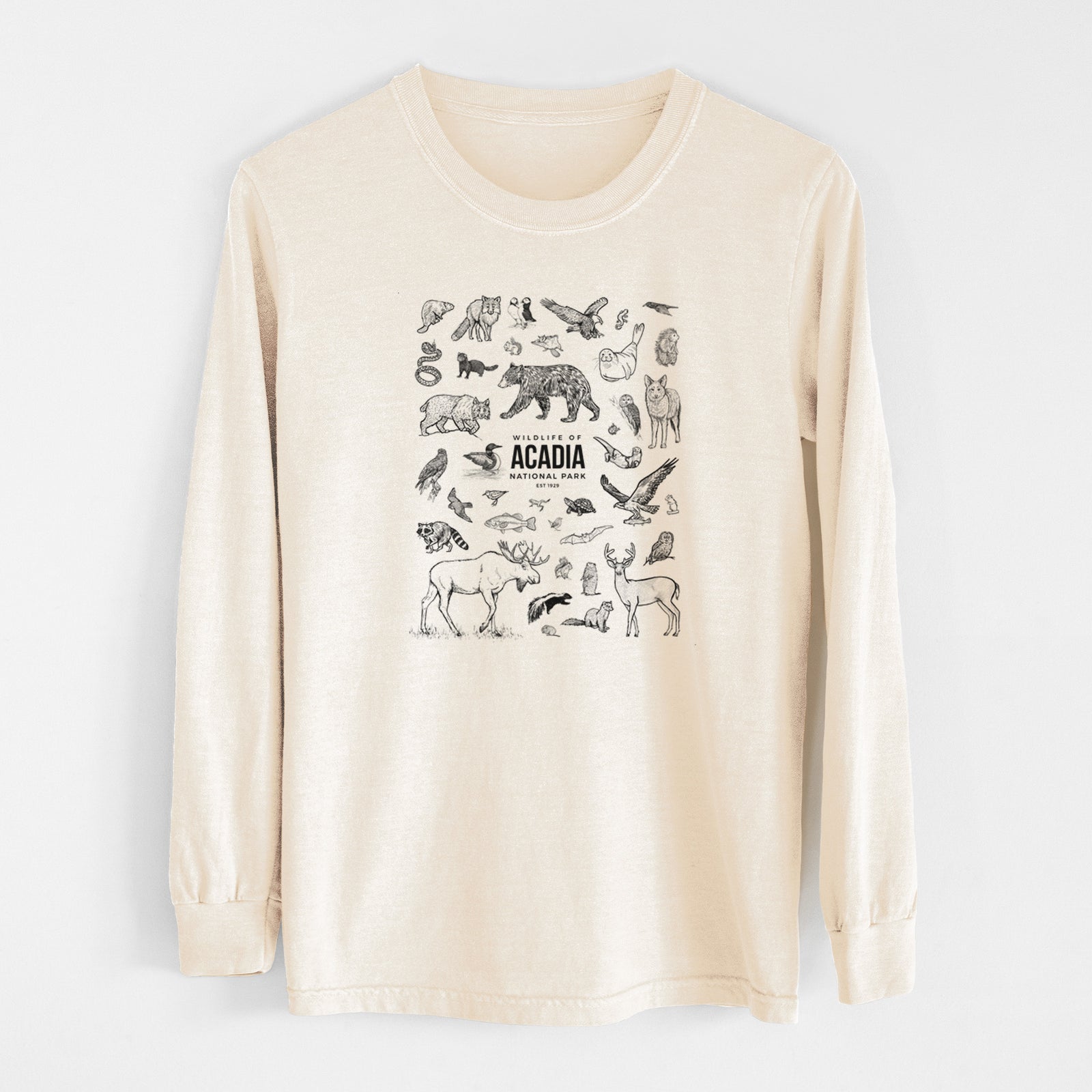Ivory Comfort Colors long sleeve shirt laid flat, printed with a collection of black ink wildlife illustrations surrounding the words Acadia National Park.