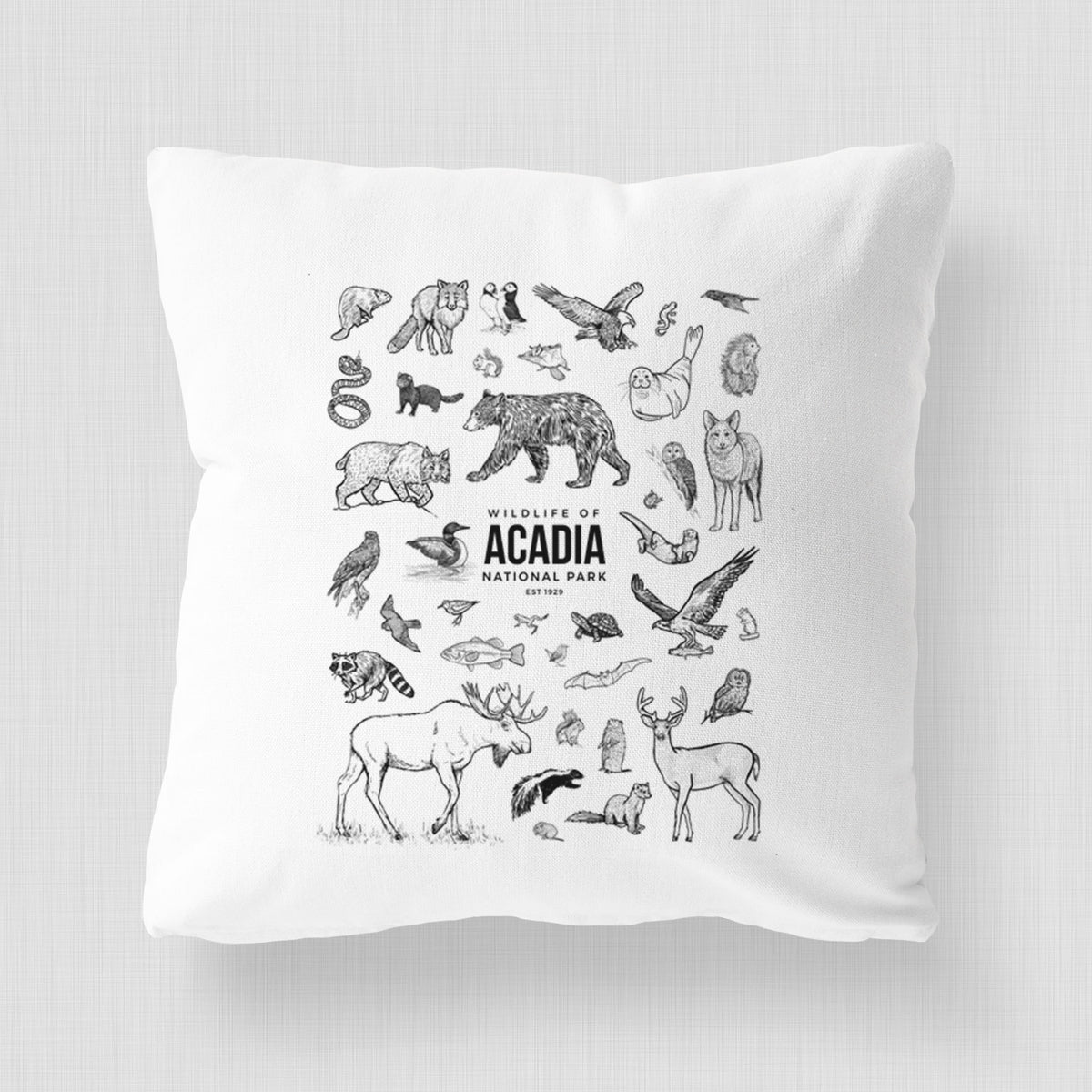 White pillow cover printed with a collection of black ink wildlife illustrations surrounding the words Acadia National Park.