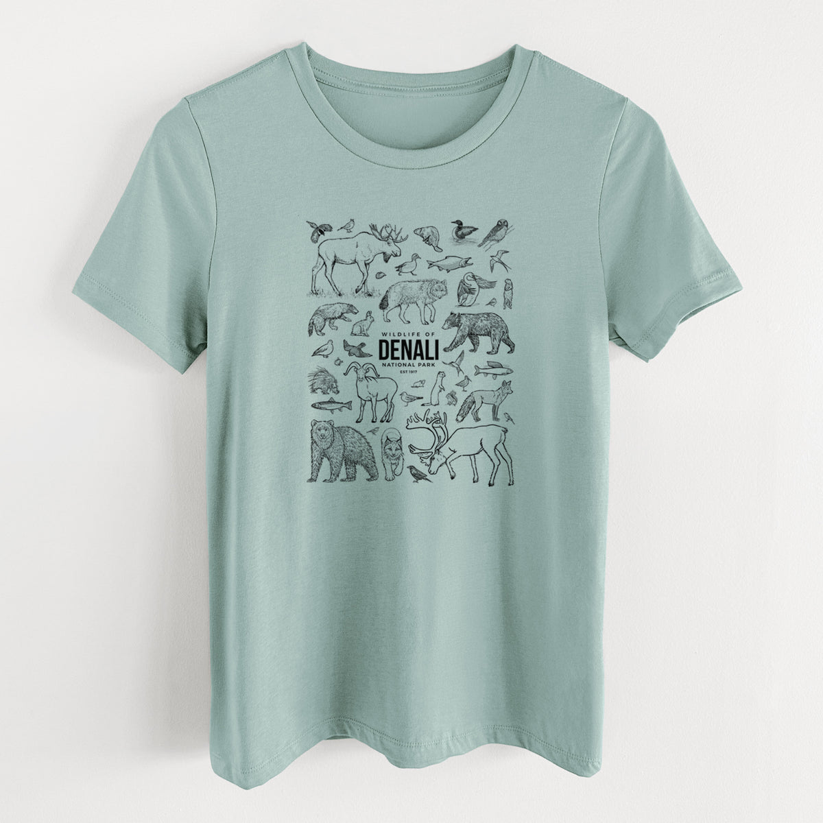 Dusty blue women's relaxed fit cotton t-shirt laid flat, printed with a collection of black ink wildlife illustrations surrounding the words Denali National Park.