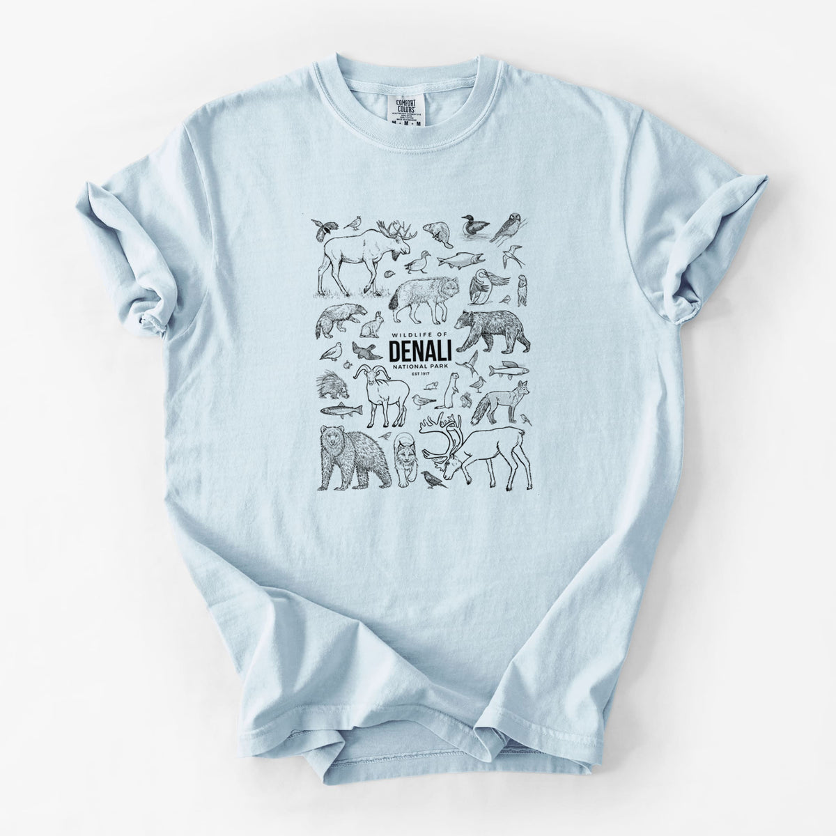 Chambray blue Comfort Colors t-shirt laid flat, printed with a collection of black ink wildlife illustrations surrounding the words Denali National Park.