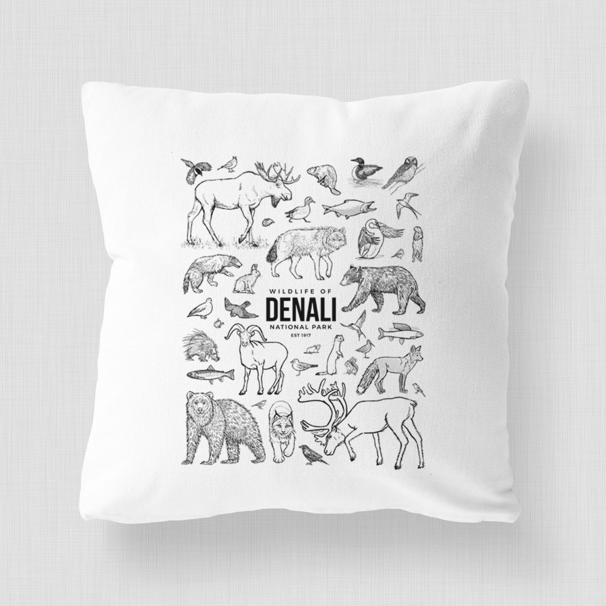 White pillow cover printed with a collection of black ink wildlife illustrations surrounding the words Denali National Park.