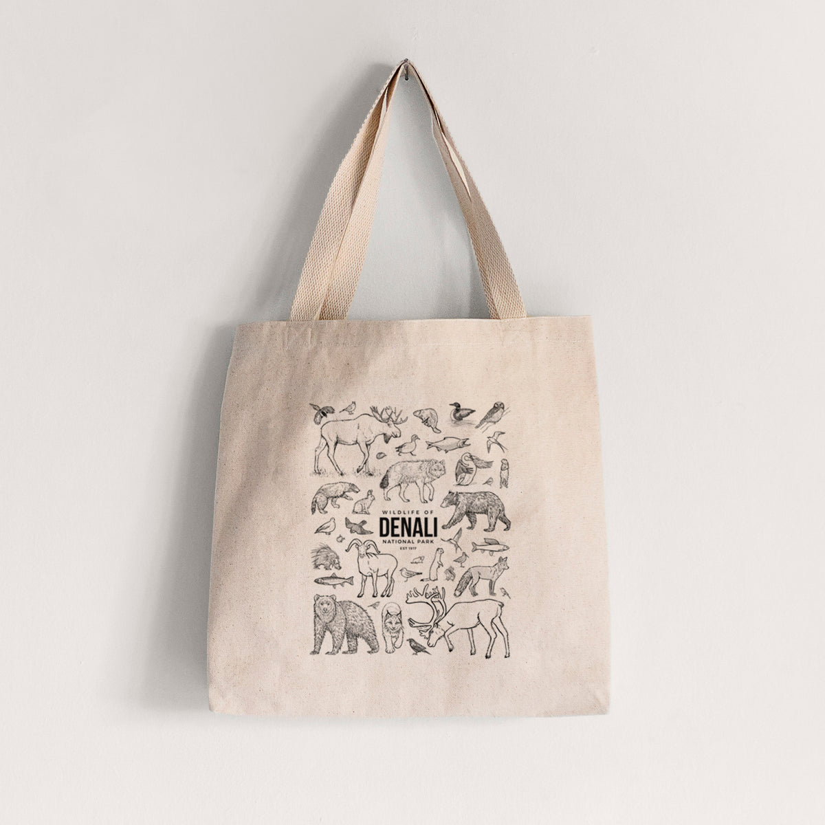 Natural canvas tote bag printed with a collection of black ink wildlife illustrations surrounding the words Denali National Park.