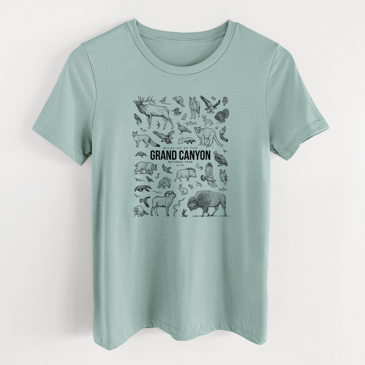 Dusty blue women's relaxed fit cotton t-shirt laid flat, printed with a collection of black ink wildlife illustrations surrounding the words Grand Canyon National Park.