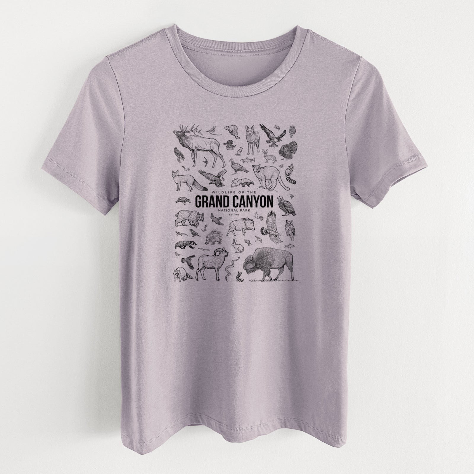 Light violet women's relaxed fit cotton t-shirt laid flat, printed with a collection of black ink wildlife illustrations surrounding the words Grand Canyon National Park.