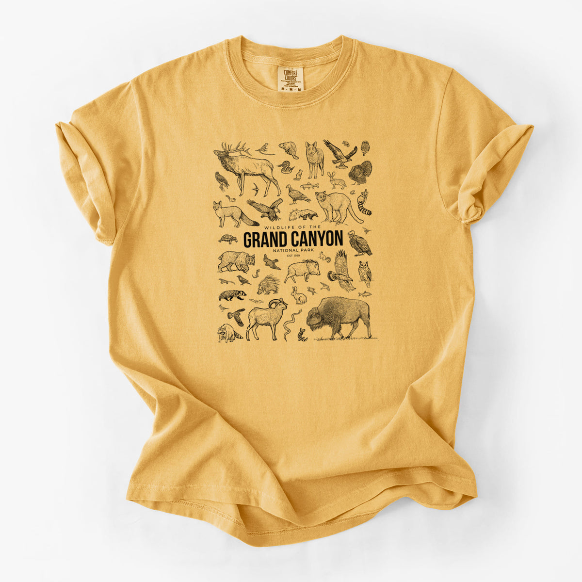 Golden wheat yellow Comfort Colors t-shirt laid flat, printed with a collection of black ink wildlife illustrations surrounding the words Grand Canyon National Park.